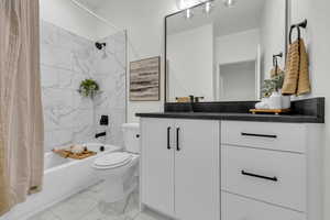 Full bathroom with shower / bathtub combination with curtain, vanity, and light marble finish floors