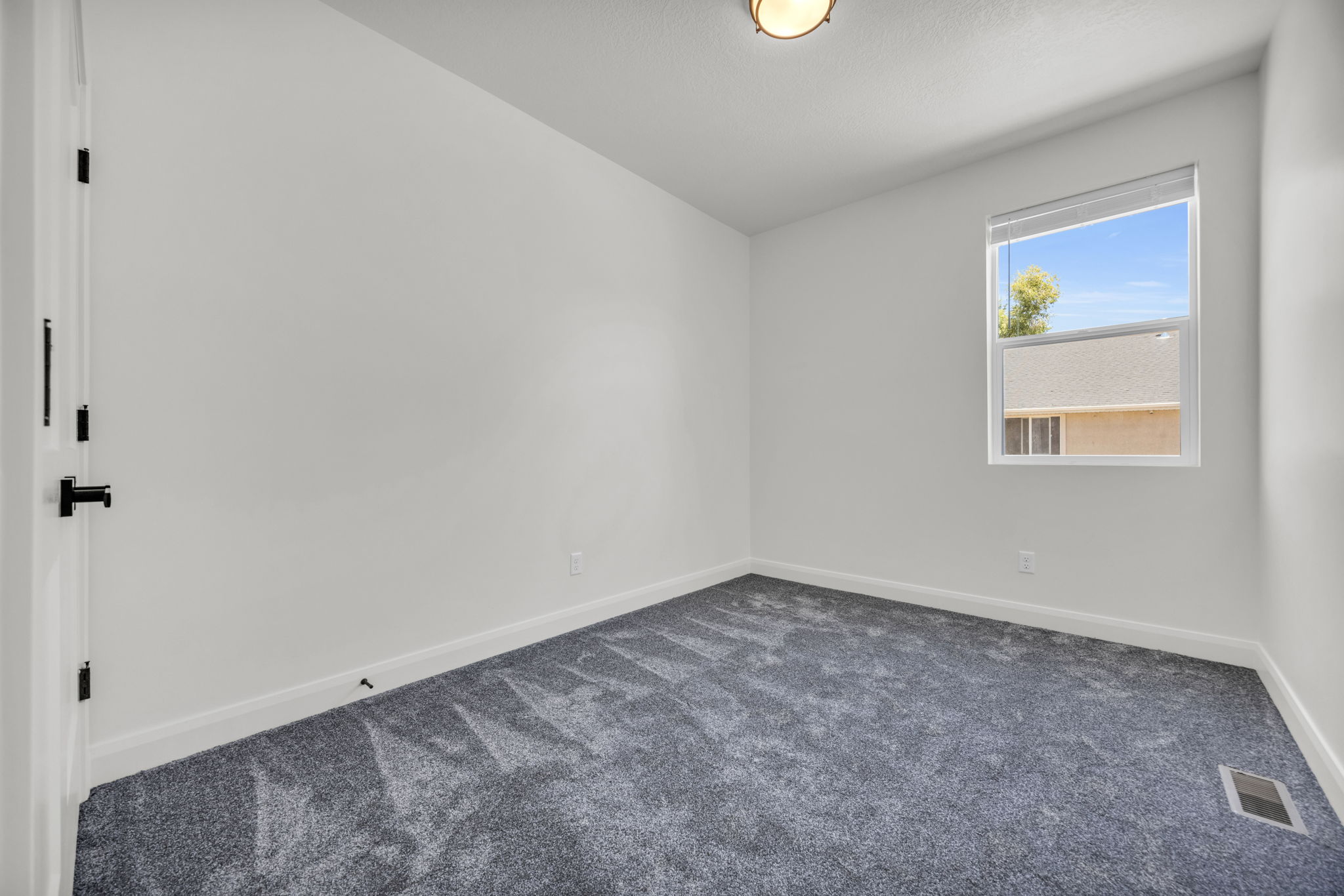 Spare room featuring dark carpet and baseboards