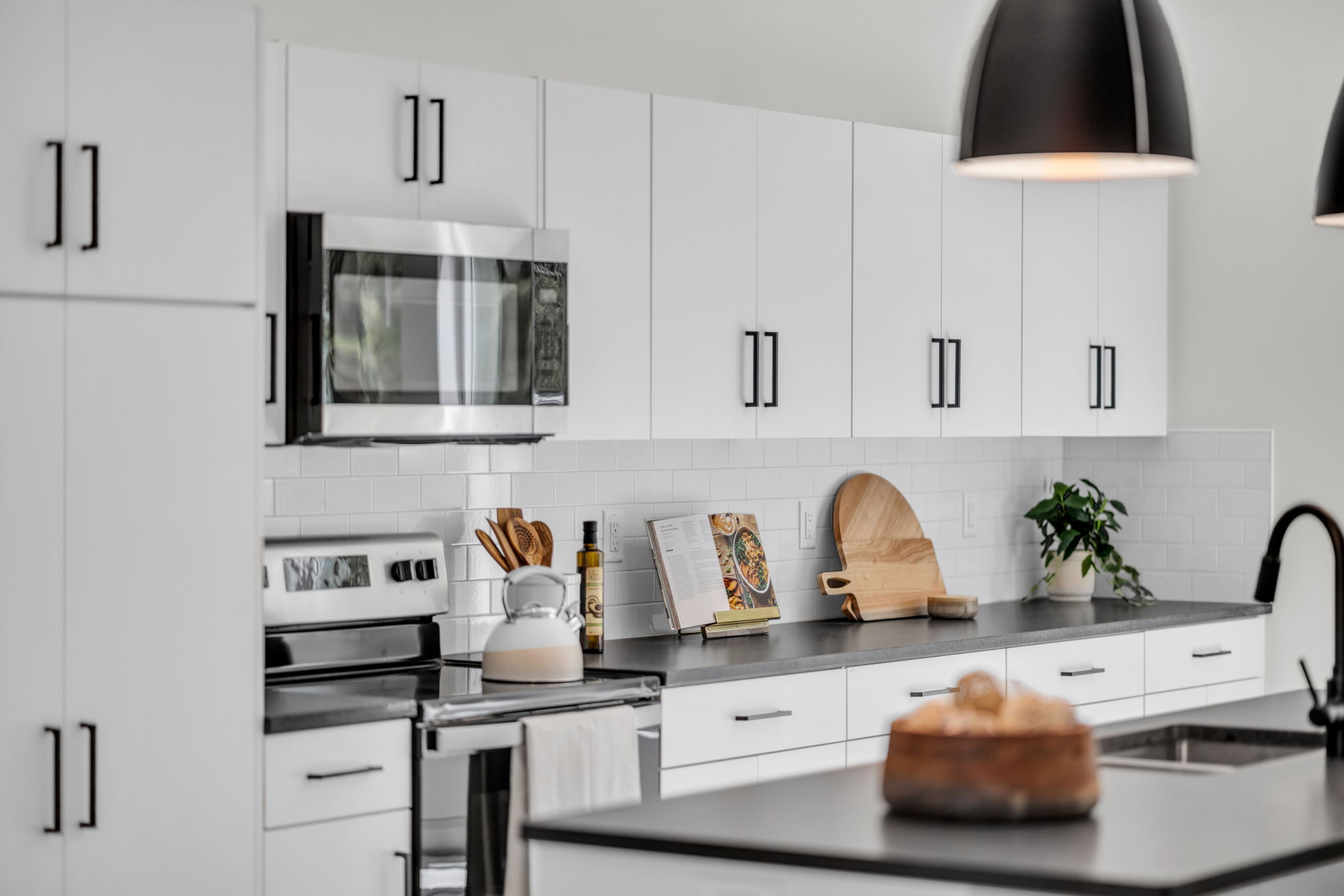 Kitchen with stainless steel appliances, dark countertops, white cabinetry, and tasteful backsplash