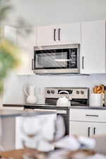 Kitchen view of appliances with stainless steel finishes, white cabinets, and tasteful backsplash