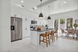 Kitchen with appliances with stainless steel finishes, light marble finish floors, decorative light fixtures, a center island with sink, and a breakfast bar area