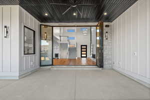 Property entrance featuring board and batten siding, ceiling fan, stone siding, and a patio area