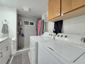 Laundry area with a textured ceiling, washer and clothes dryer, and cabinet space