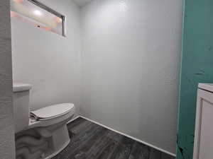 Half bathroom featuring dark wood-type flooring and a textured wall