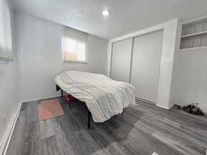 Bedroom featuring a textured ceiling, wood finished floors, and a closet