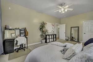 Carpeted bedroom featuring a ceiling fan and an office area
