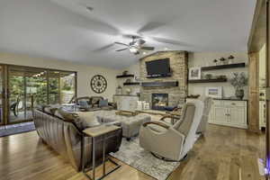 Living area featuring light wood finished floors, lofted ceiling, a fireplace, and ceiling fan
