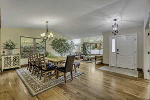 Dining room featuring a chandelier, light wood-style floors, and lofted ceiling