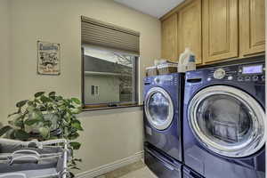 Laundry area with separate washer and dryer, cabinet space, and light tile patterned floors