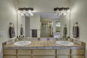 Bathroom featuring a bath, double vanity, and a stall shower