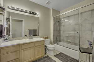 Bathroom featuring shower / bath combination with glass door, vanity, and light tile patterned floors