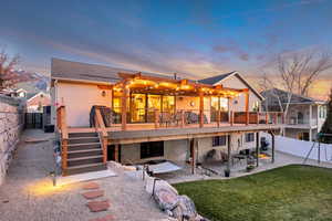 Back of property at dusk with a fenced backyard, a patio area, stucco siding, roof with shingles, and a wooden deck