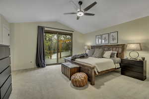 Bedroom with access to exterior, light colored carpet, vaulted ceiling, and ceiling fan