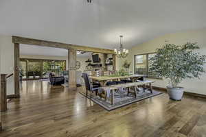 Dining area with light wood finished floors, plenty of natural light, a chandelier, and vaulted ceiling
