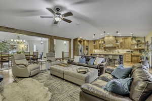 Living area featuring ceiling fan, vaulted ceiling, a chandelier, and light wood-type flooring