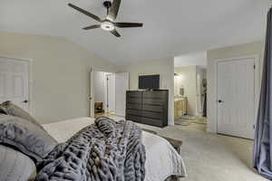 Bedroom with light colored carpet, lofted ceiling, a ceiling fan, and connected bathroom