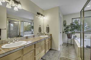 Full bath with a garden tub, double vanity, a shower stall, and light tile patterned floors