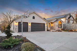 View of front facade with stone siding, concrete driveway, a garage, and stucco siding