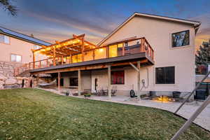 Rear view of property featuring a patio, a lawn, stucco siding, and stairs