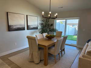 Dining room with vaulted ceiling, a chandelier, and light wood-style flooring