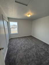 Unfurnished bedroom with dark carpet, a closet, and a textured ceiling