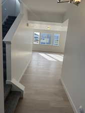 Hallway with stairs and light wood-style floors