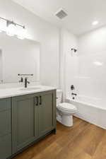 Bathroom with vanity, dark wood-type flooring, and shower / bathtub combination