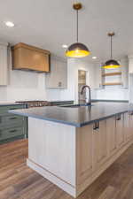 Kitchen featuring tasteful backsplash, a large island with sink, decorative light fixtures, dark wood-type flooring, and a textured ceiling