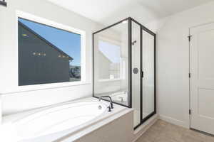 Bathroom featuring a bath, a stall shower, and light tile patterned flooring