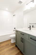 Full bath featuring vanity, dark wood finished floors, and tub / shower combination