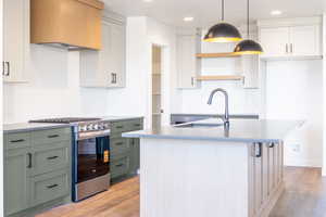 Kitchen featuring tasteful backsplash, gas range, white cabinets, and recessed lighting