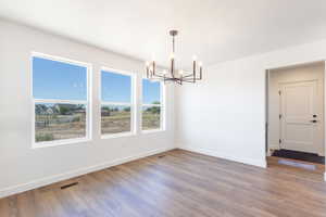 Unfurnished dining area with a chandelier and wood finished floors