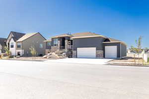 View of front of property with concrete driveway, a garage, a residential view, and stone siding