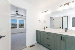 Bathroom with double vanity, a shower stall, light carpet, and ceiling fan