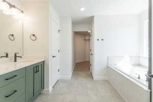 Full bath featuring vanity, a spacious closet, a garden tub, and recessed lighting
