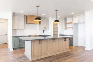 Kitchen with an island with sink, decorative light fixtures, light wood-type flooring, recessed lighting, and gray cabinets