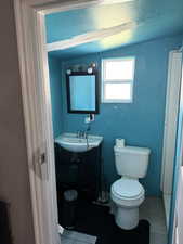 Half bath with light tile patterned floors and vanity