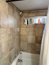 Full bath featuring shower / bath combo and a textured ceiling
