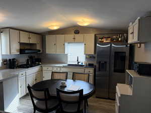 Kitchen with black appliances, dark wood finished floors, lofted ceiling, ventilation hood, and open shelves