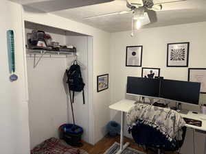 Office area with a textured ceiling, wood finished floors, and a ceiling fan