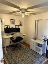 Office with wood finished floors, a textured ceiling, and a ceiling fan