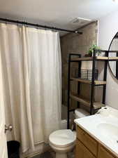 Full bathroom with shower / bathtub combination with curtain, a textured ceiling, and vanity