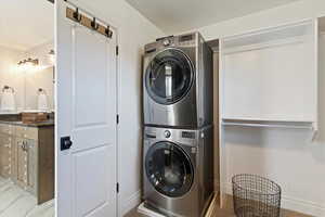 Laundry room with stacked washer / dryer and light marble finish flooring
