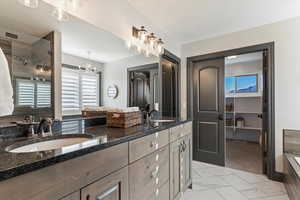 Bathroom featuring double vanity, light marble finish flooring, and a shower with shower door