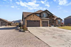 Craftsman inspired home featuring stone siding, concrete driveway, board and batten siding, a mountain view, and a standing seam roof