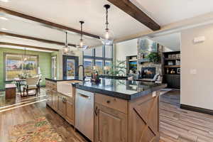Kitchen featuring hanging light fixtures, a stone fireplace, dark wood-style flooring, and beam ceiling