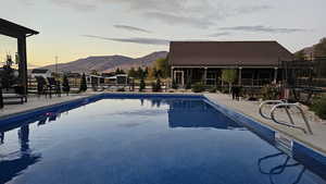 Pool at dusk featuring a mountain view and a patio
