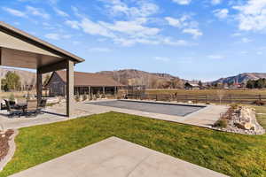 View of swimming pool featuring a patio, a mountain view, a game area, and a rural view