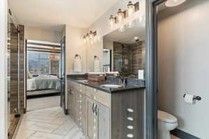 Ensuite bathroom featuring double vanity, light marble finish flooring, and a shower stall
