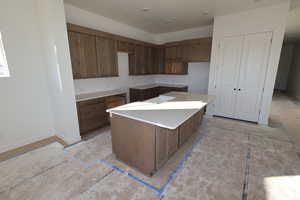Kitchen with a center island, brown cabinets, light countertops, and a breakfast bar